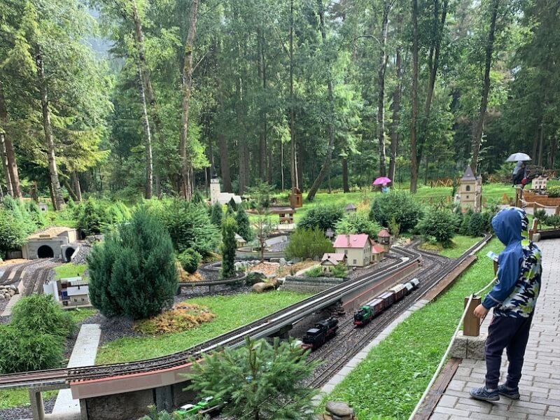 Chlapec sleduje koľajnice s vláčikom v parku miniatúr s rôznymi atrakciami.