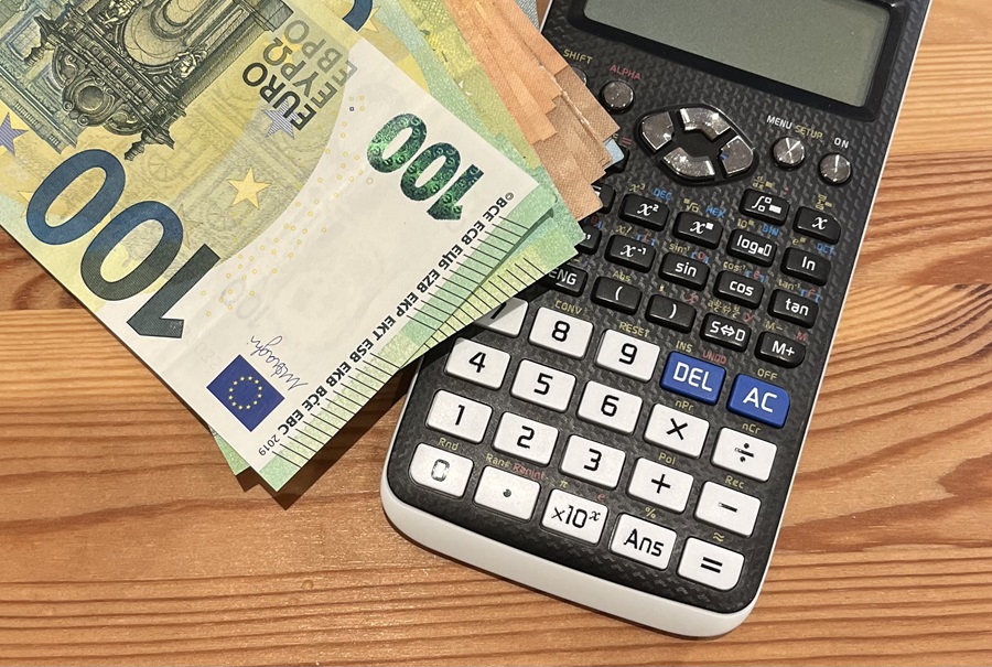 kalkulačka a eurové bankovky v rôznych hodnotách na drevenom stole