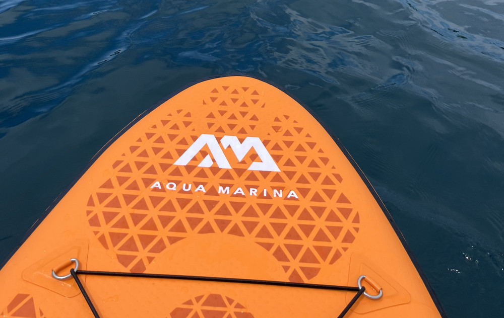 Oranžový paddleboard na pokojnej morskej hladine.