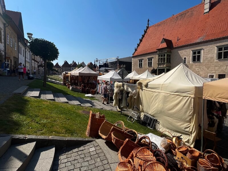 Jarmočné stánky na ulici s košíkmi a tradičnými kožušinami.