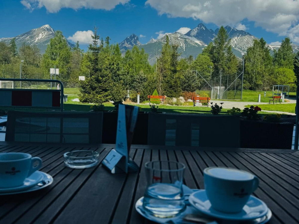Dve kávy na drevenom stole terasy s výhľadom na Tatry.